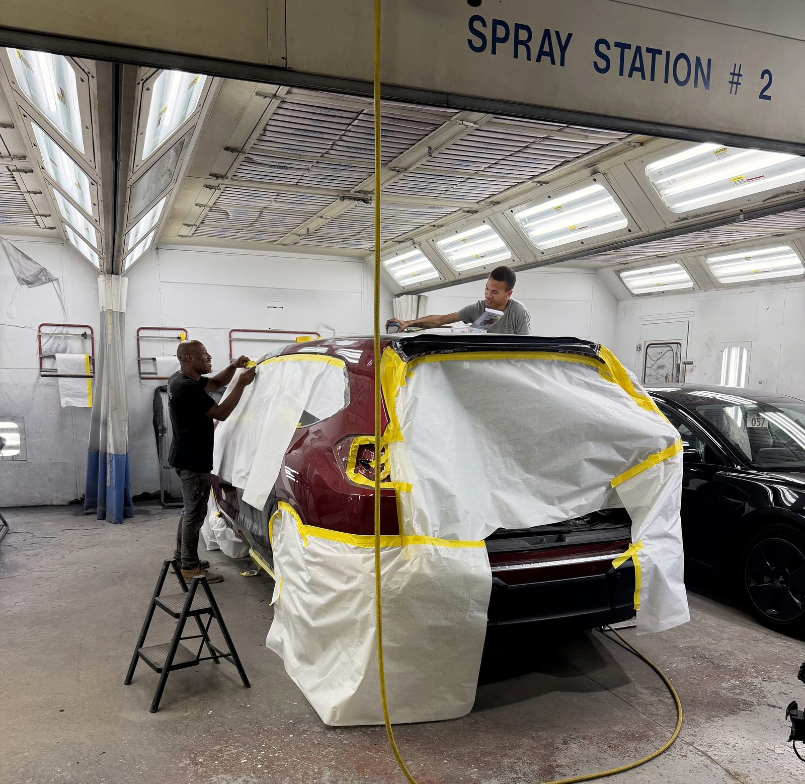 Our technicians masking a red SUV for paint in our spray booth