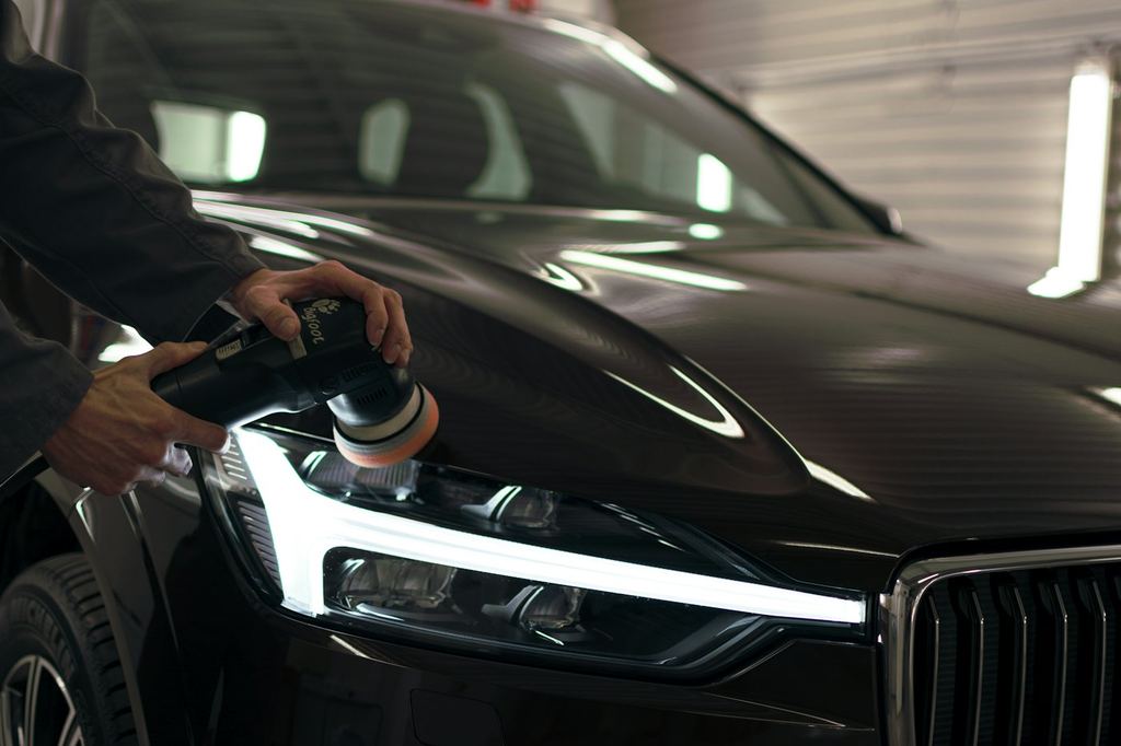 A technician polishing a headlight on a finished car